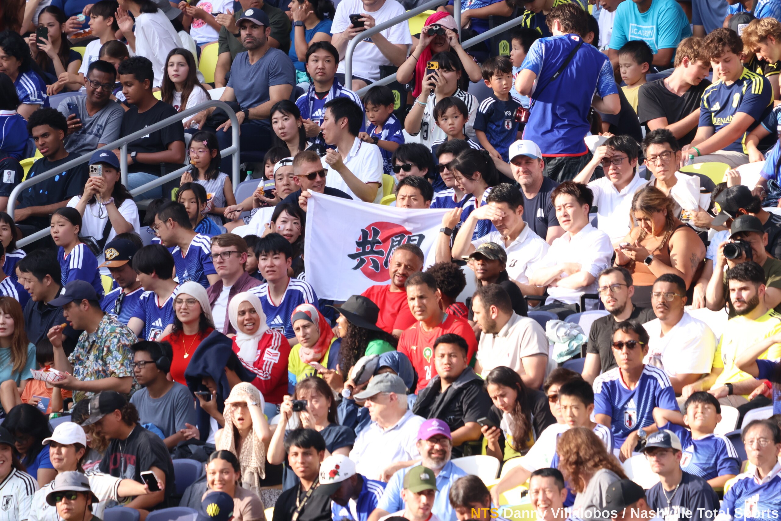 Aficionados japoneses en GEODIS Park sostienen bandera con el kanji kyoto que significa luchar juntos