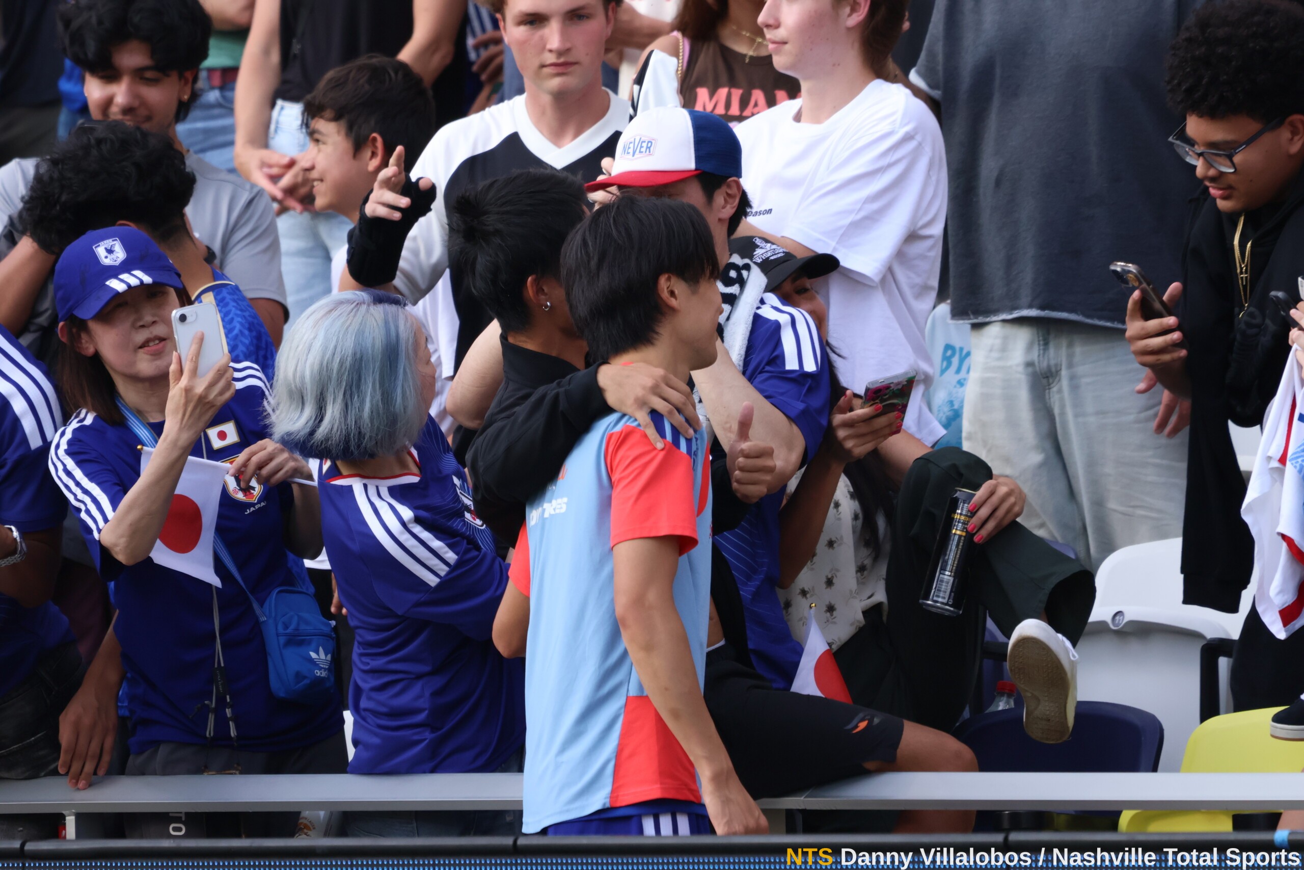 Jugador de Japón se toma selfies con aficionados en la grada de GEODIS Park durante el entrenamiento abierto