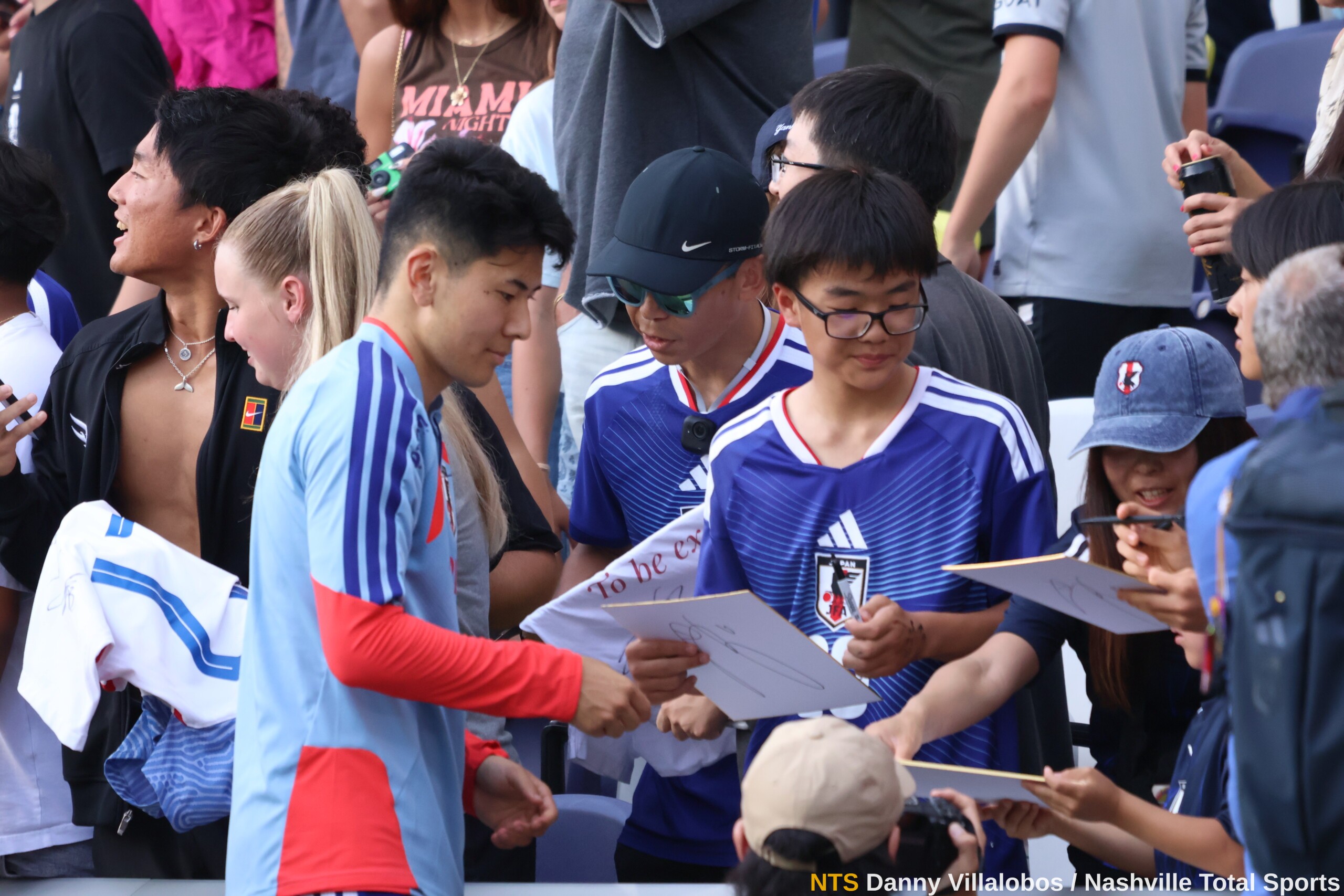 Niños aficionados acercan shikishi tablas japonesas de autógrafos a los jugadores de Japón en Nashville